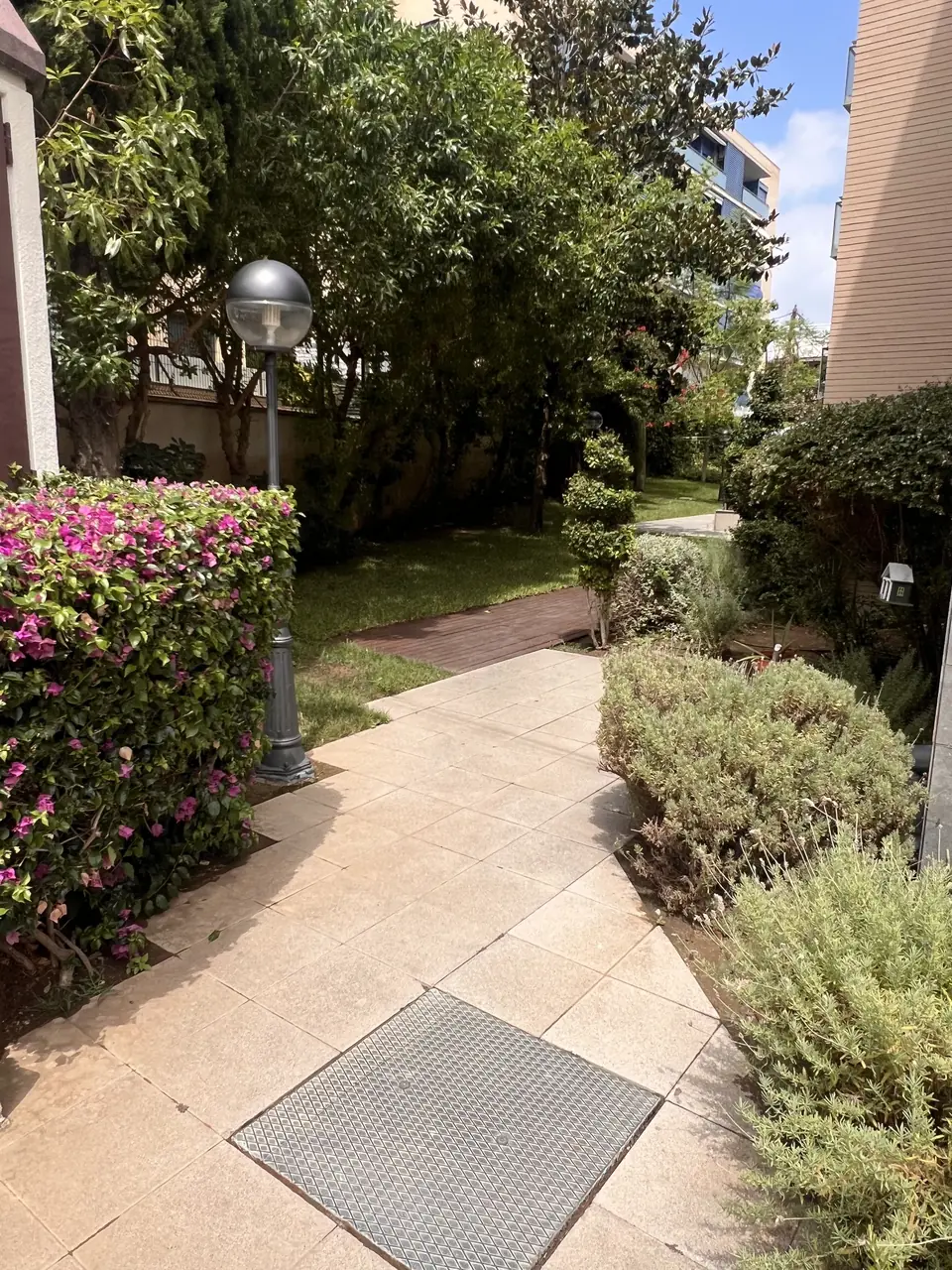 Jardín de comunidad con buganvilla, lavandas y caminos de piedra mantenidos por nosotros