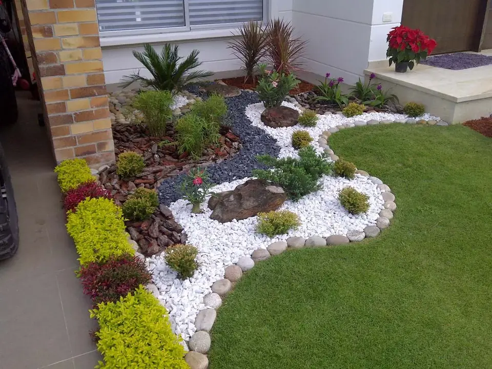 Parterre de entrada diseñado por nosotros con canto blanco, piedra volcánica y plantas de color